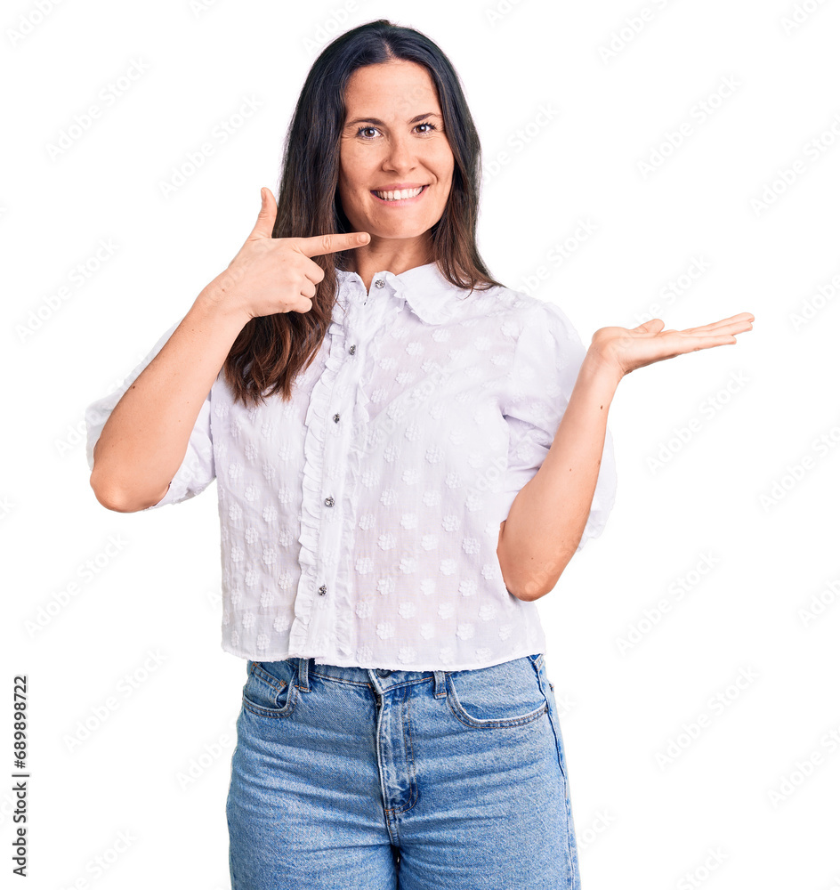 Young beautiful brunette woman wearing casual shirt amazed and smiling to the camera while presenting with hand and pointing with finger. Young beautiful brunette woman wearing casual shirt amazed and smiling to the camera while presenting with hand and pointing with finger.