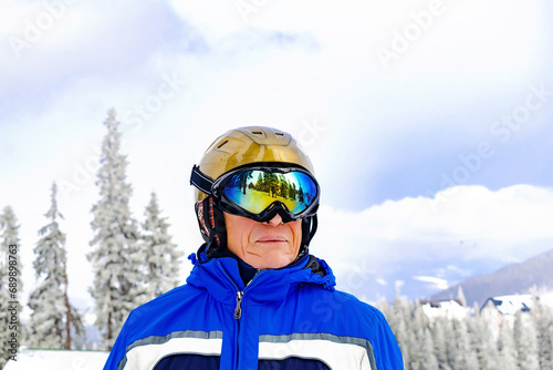 Active senior experienced mature man in overalls,ski mask on snow hill looking at high Carpathian mountains at winter alpine ski resort panorama, nature landscape,Ukraine,Europe © Дарья Воронцова