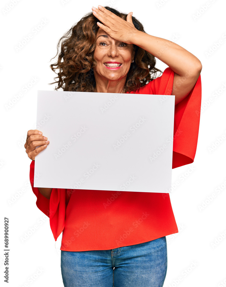 Middle age hispanic woman holding blank empty banner stressed and frustrated with hand on head, surprised and angry face