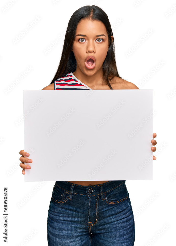 Beautiful hispanic woman holding blank empty banner scared and amazed with open mouth for surprise, disbelief face Beautiful hispanic woman holding blank empty banner scared and amazed with open mouth for surprise, disbelief face