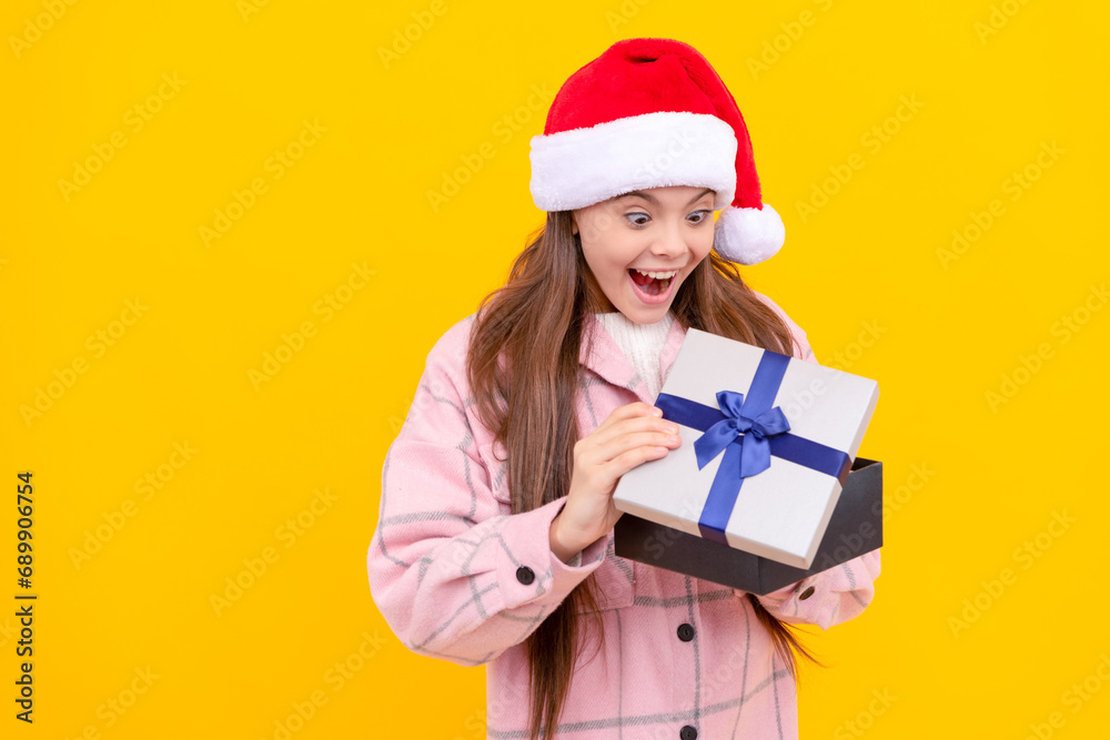 surprised child in santa claus hat hold present box on yellow background, boxing day surprised child in santa claus hat hold present box on yellow background, boxing day