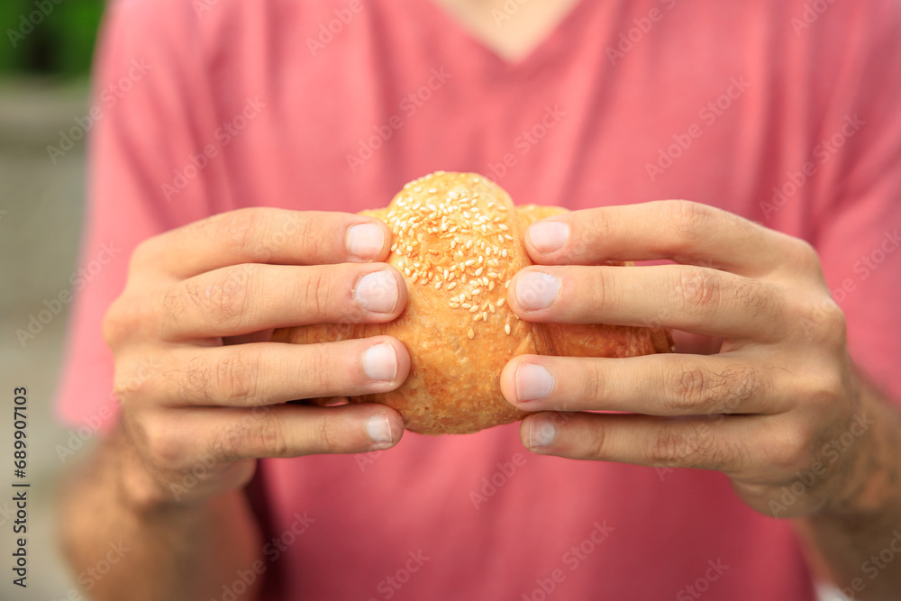 Guy's hand holds a croissant, snack and fast food concept. Selective focus on hands with blurred background Guy's hand holds a croissant, snack and fast food concept. Selective focus on hands with blurred background