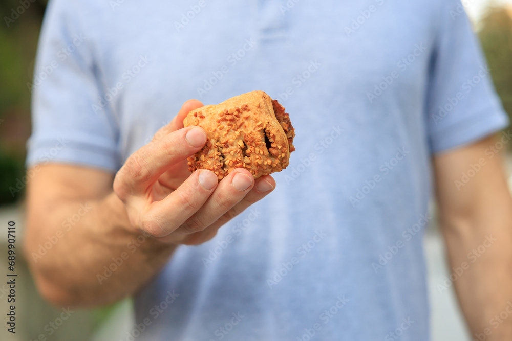 A man's hand holds sweet pastry with jam, snack and fast food concept. Selective focus on hands with blurred background A man's hand holds sweet pastry with jam, snack and fast food concept. Selective focus on hands with blurred background