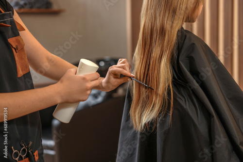 Professional hairdresser working with girl in beauty salon, closeup photo
