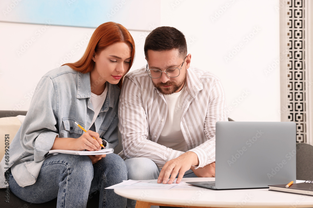 Couple doing taxes at table in living room Couple doing taxes at table in living room