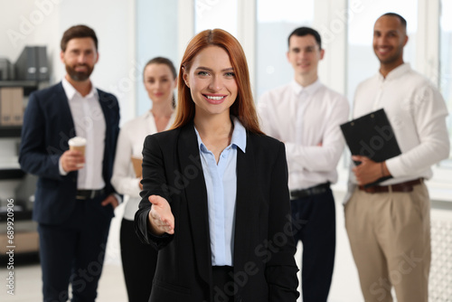 Group of people in office. Happy woman welcoming and offering handshake indoors