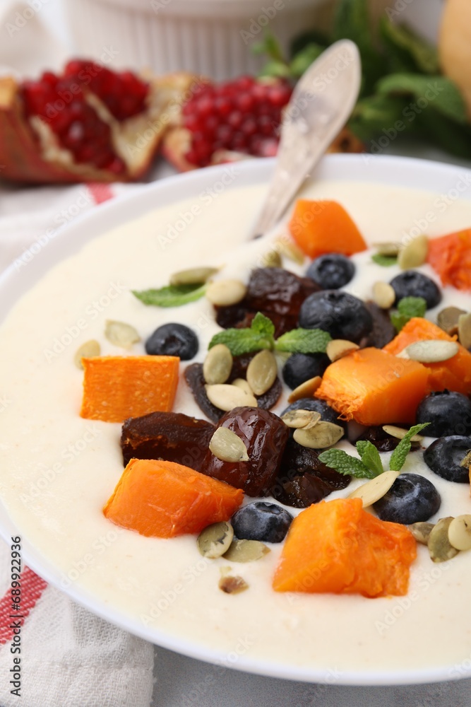 Delicious semolina pudding with blueberries, dates, pumpkin and mint in bowl on table, closeup Delicious semolina pudding with blueberries, dates, pumpkin and mint in bowl on table, closeup