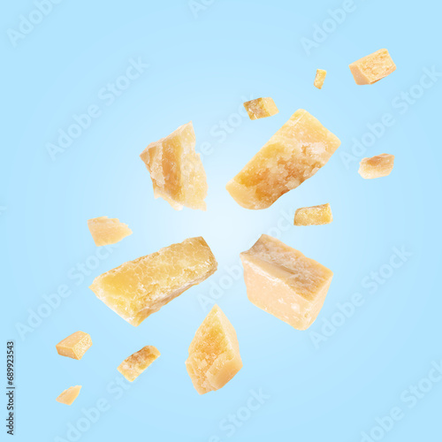 Parmesan cheese in air on light blue background
