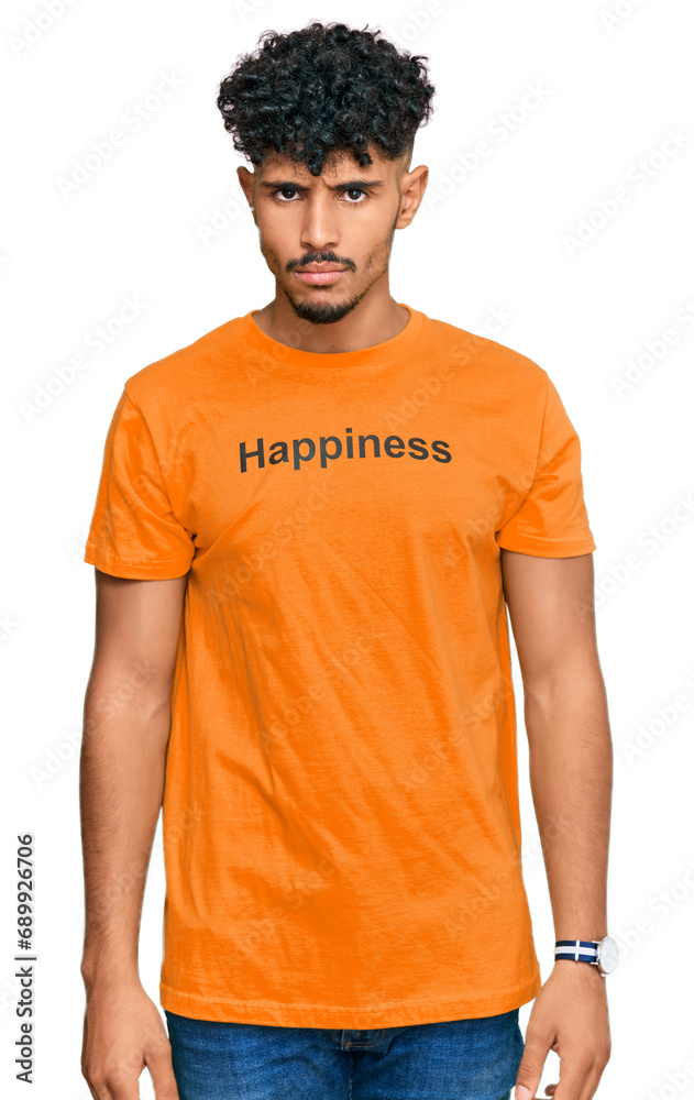 Young arab man wearing tshirt with happiness word message skeptic and nervous, frowning upset because of problem. negative person. Young arab man wearing tshirt with happiness word message skeptic and nervous, frowning upset because of problem. negative person.