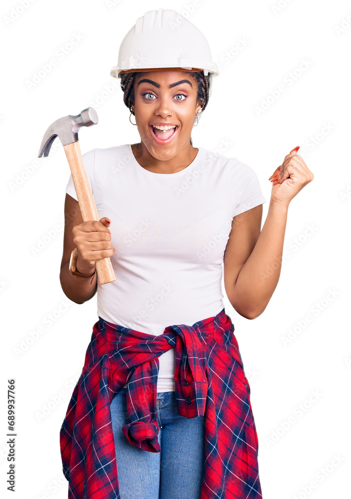 Young african american woman with braids wearing hardhat holding hammer screaming proud, celebrating victory and success very excited with raised arms Young african american woman with braids wearing hardhat holding hammer screaming proud, celebrating victory and success very excited with raised arms