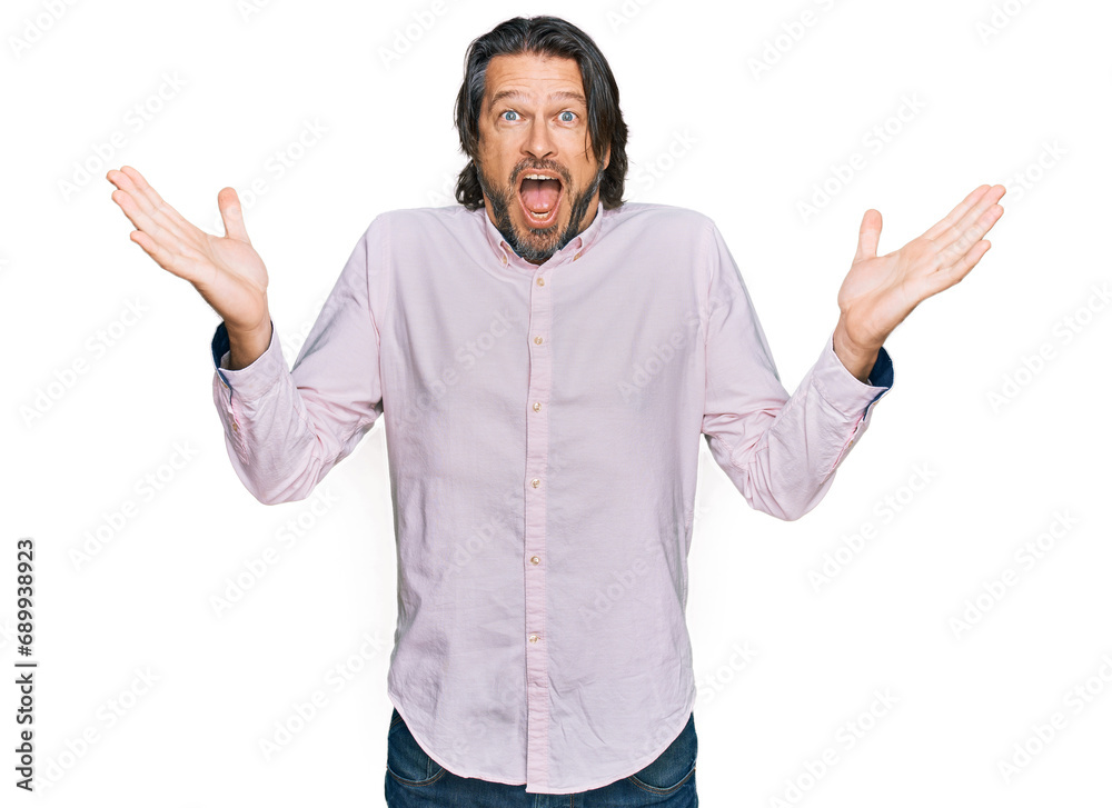Middle age handsome man wearing business shirt celebrating crazy and amazed for success with arms raised and open eyes screaming excited. winner concept Middle age handsome man wearing business shirt celebrating crazy and amazed for success with arms raised and open eyes screaming excited. winner concept