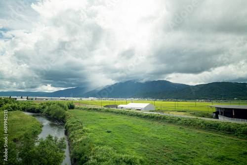 Japanese farms growing green plants outside of Kyoto, Japan as seen from the Tokido Shinkansen line with mountains in the background