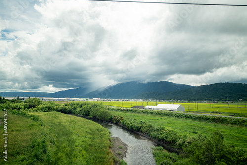 Japanese farms growing green plants outside of Kyoto, Japan as seen from the Tokido Shinkansen line with mountains in the background photo
