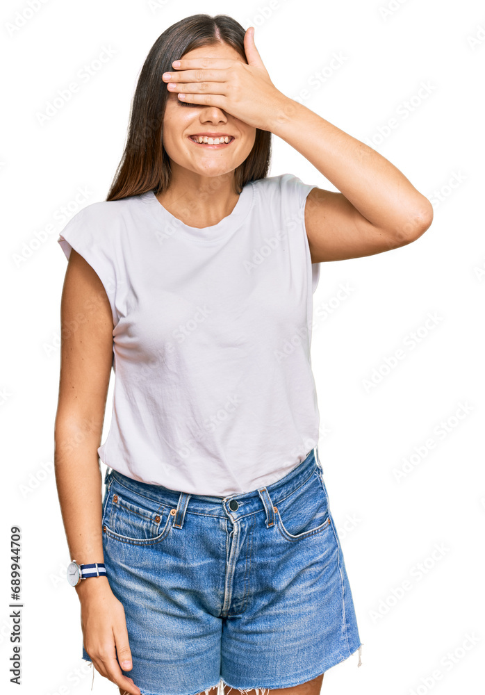Young caucasian woman wearing casual white tshirt smiling and laughing with hand on face covering eyes for surprise. blind concept. Young caucasian woman wearing casual white tshirt smiling and laughing with hand on face covering eyes for surprise. blind concept.