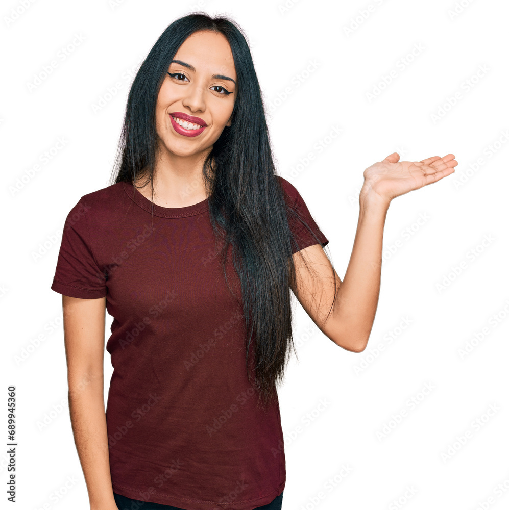 Fototapeta premium Young hispanic girl wearing casual t shirt smiling cheerful presenting and pointing with palm of hand looking at the camera.