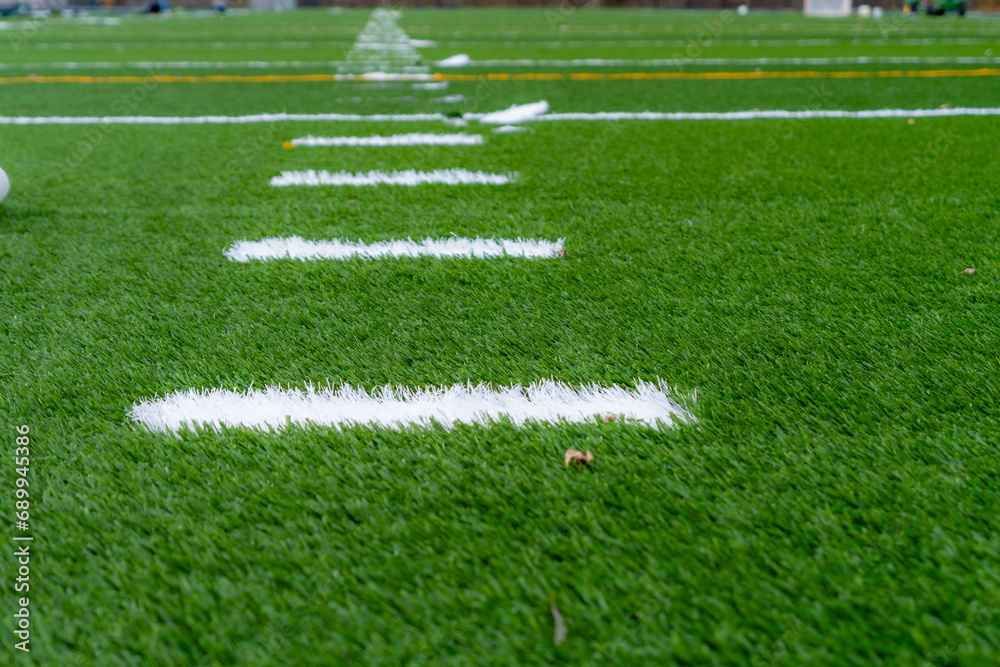 Synthetic turf field under construction with lines and graphics being installed.	
