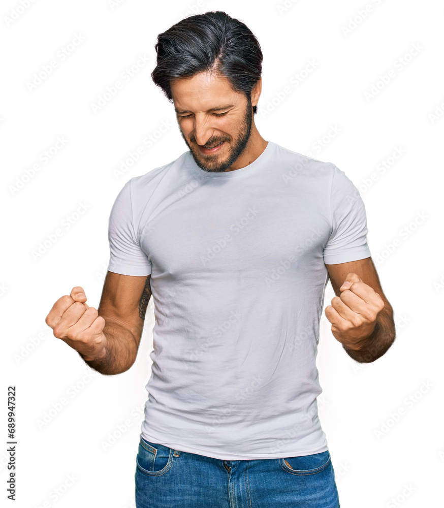 Young hispanic man wearing casual white t shirt excited for success with arms raised and eyes closed celebrating victory smiling. winner concept. Young hispanic man wearing casual white t shirt excited for success with arms raised and eyes closed celebrating victory smiling. winner concept.