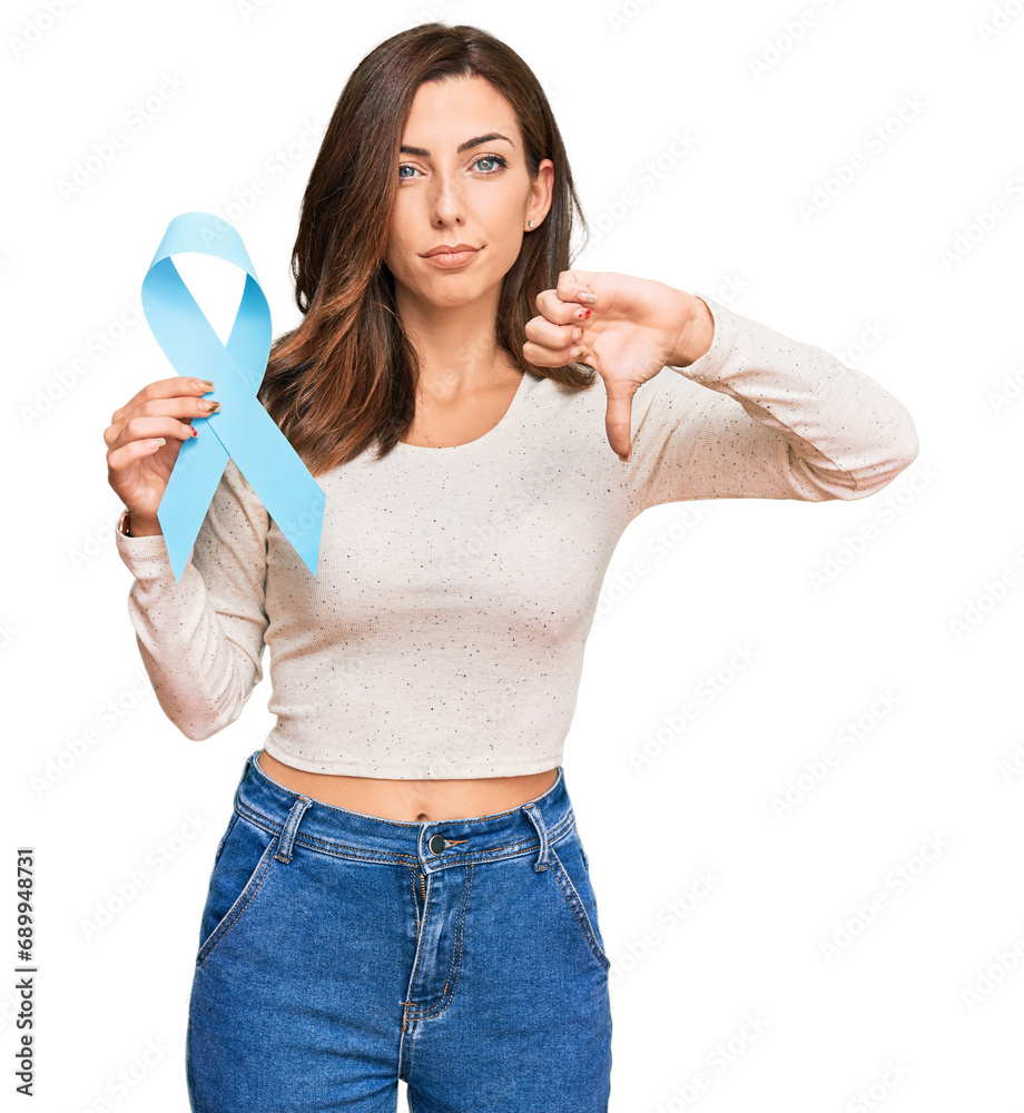Young brunette woman holding blue ribbon with angry face, negative sign showing dislike with thumbs down, rejection concept Young brunette woman holding blue ribbon with angry face, negative sign showing dislike with thumbs down, rejection concept