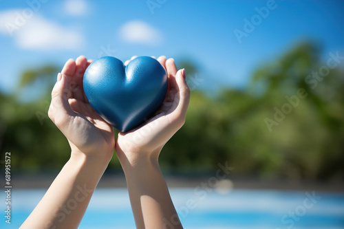 Woman hands holding a blue heart against the blue sky. Love concept.