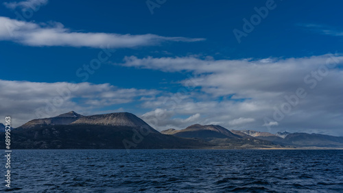 A picturesque mountain range of the Andes against a background of blue sky and clouds. View from the Beagle Canal. Ripples on the water. Argentina. Tierra del Fuego Archipelago © Вера 