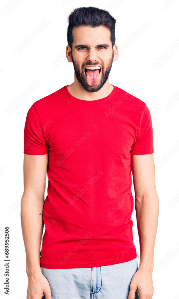 Young handsome man with beard wearing casual t-shirt sticking tongue out happy with funny expression. emotion concept. Young handsome man with beard wearing casual t-shirt sticking tongue out happy with funny expression. emotion concept.