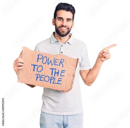 Young handsome man with beard holding power to the people cardboard banner smiling happy pointing with hand and finger to the side photo