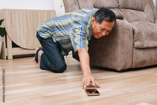 Elderly older grandfather having an accident falling on the home floor, trying to reach out smartphone.