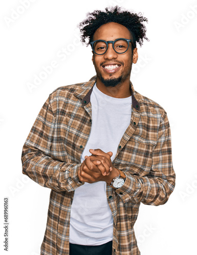 Foto Young african american man with beard wearing casual clothes and glasses with hands together and crossed fingers smiling relaxed and cheerful