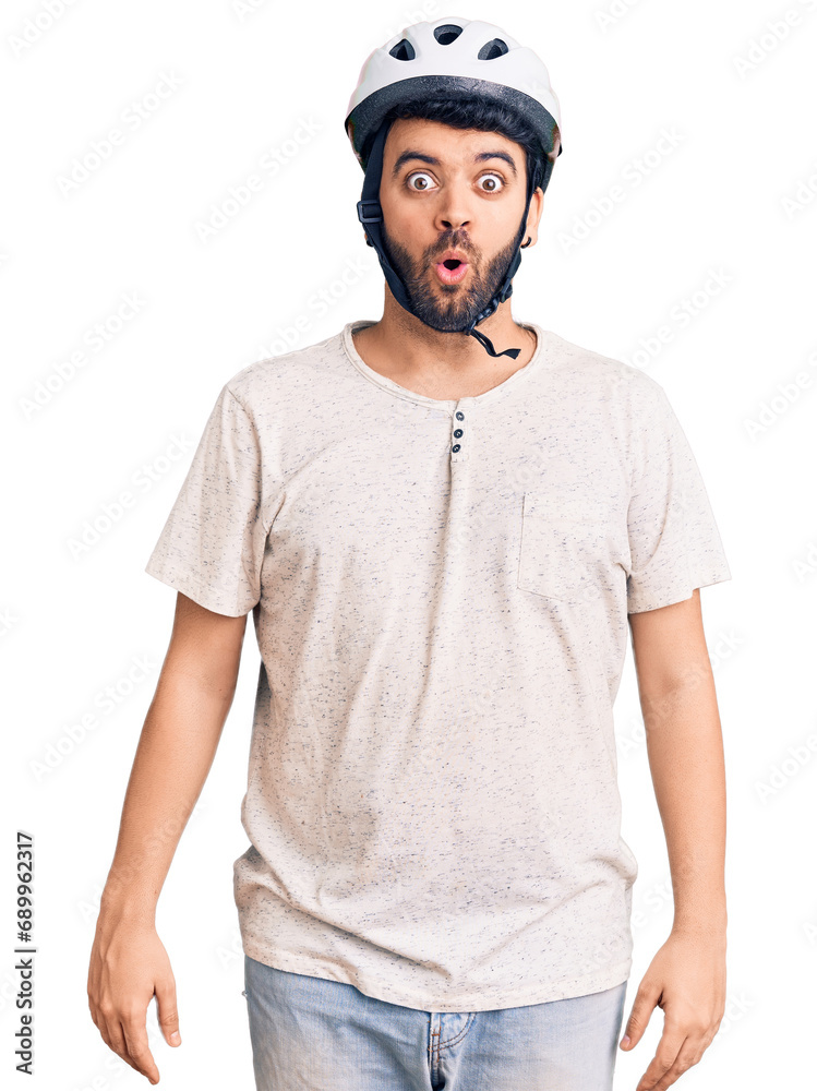 Young hispanic man wearing bike helmet scared and amazed with open mouth for surprise, disbelief face Young hispanic man wearing bike helmet scared and amazed with open mouth for surprise, disbelief face