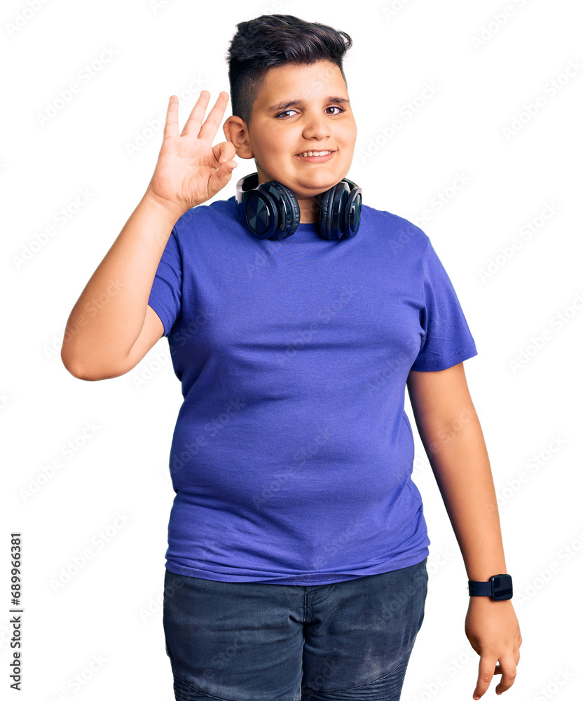Fototapeta premium Little boy kid listening to music wearing headphones smiling positive doing ok sign with hand and fingers. successful expression.