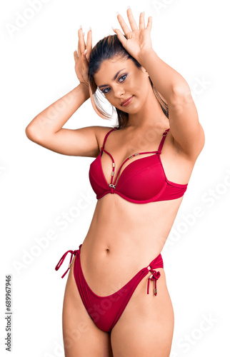 Young beautiful woman wearing bikini doing bunny ears gesture with hands palms looking cynical and skeptical. easter rabbit concept. © Krakenimages.com