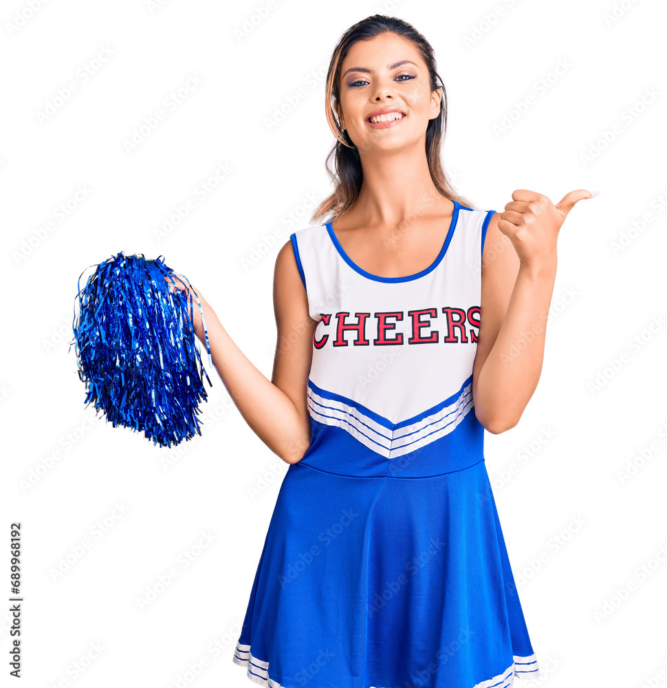 Young beautiful woman wearing cheerleader uniform pointing to the back behind with hand and thumbs up, smiling confident Young beautiful woman wearing cheerleader uniform pointing to the back behind with hand and thumbs up, smiling confident