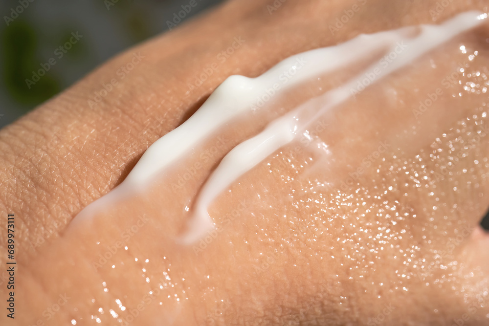 Fototapeta premium A smear of white moisturizer or sunscreen on a woman's hand.