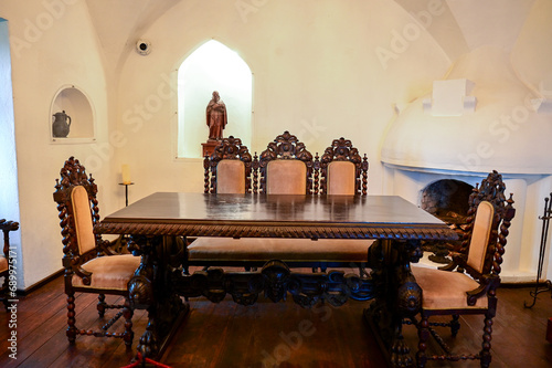 Antique table with antique chairs in the old walls of the Dracula Castle or Bran Castle, Törzburg or Castelul Bran in Bran Village, Transylvania in Romania, 16.07.2023 photo