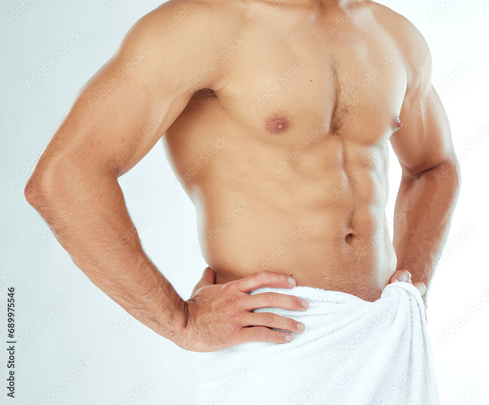 Fototapeta premium Fitness, body and closeup of man in a towel in studio for shower, wellness or grooming on white background. Chest, stomach and male model in a bathroom for cosmetic, care or cleaning with a sixpack