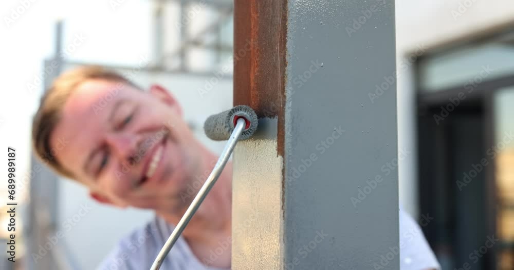 Positive male houseworker paints new railings on balcony Positive male houseworker paints new railings on balcony