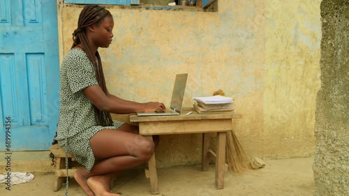 Browsing the internet while studying online, the young woman is getting access to education from her village in Kumasi, Ghana, in Africa. photo