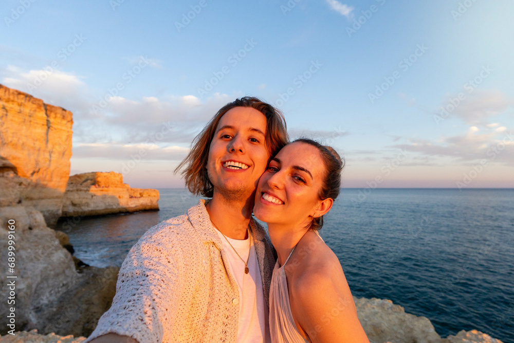 Embracing Love at Sunset: A Close-Up, selfie of a Couple on a Cliff Overlooking the Ocean at Sunset while on summer holidays.