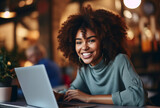 Attractive young black woman sitting in front of a laptop smiling