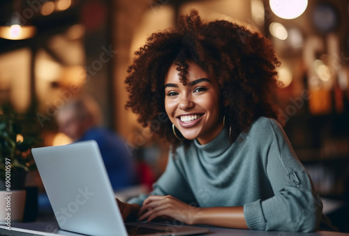 Attractive young black woman sitting in front of a laptop smiling