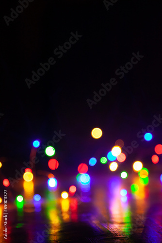 Bright round blurry lights are chaotically located below black background....