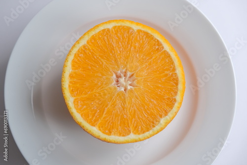 ripe and juicy orange. fresh orange cut in half on a white plate
