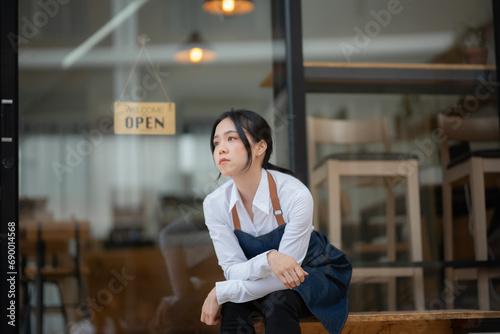 A young coffee shop employee is opening a shop for service.