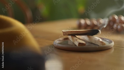 Hand Places Burning Palo Santo Stick (Holy Wood) On Table. closeup, static shot photo