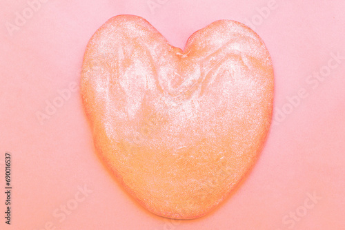Peach Fuzz glitter slime in the form of a heart on pink background.