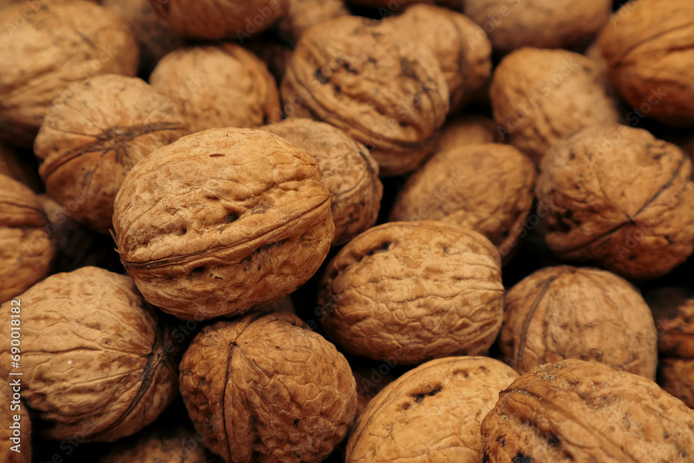 Walnuts in a shell. Background with many walnuts. Ripe walnut sold in the market Walnuts in a shell. Background with many walnuts. Ripe walnut sold in the market