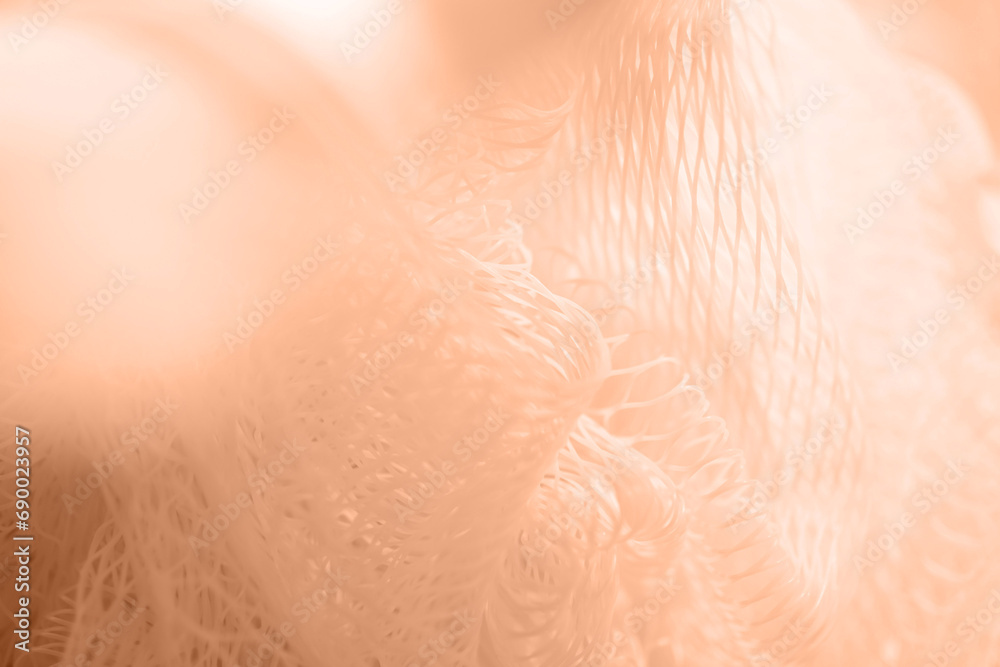 Fototapeta premium Texture of a colored nylon washcloth close-up. Color peach fuzz