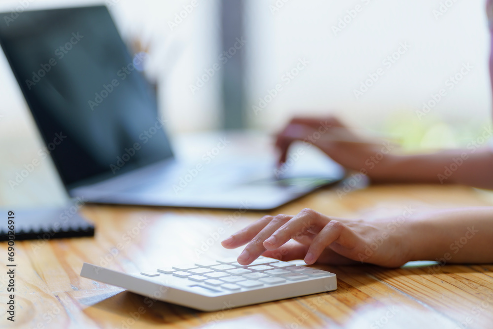 Close-up portrait of businesswoman accountant using calculator and laptop for matching financial data saving in office room, Business financial, tax, accounting concept.