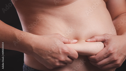 Closeup of man fat belly with hand holding on it. Obesity body, overweight and health problem from unhealthy eating lifestyle concept.