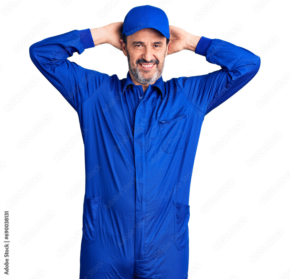 Middle age handsome man wearing mechanic uniform relaxing and stretching, arms and hands behind head and neck smiling happy Middle age handsome man wearing mechanic uniform relaxing and stretching, arms and hands behind head and neck smiling happy